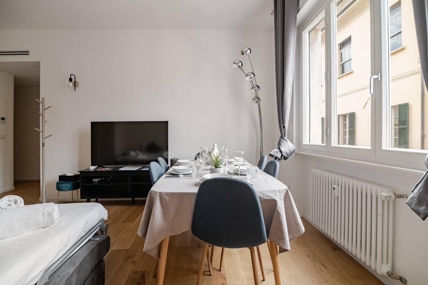 Ein kleines Hotelzimmer mit Essbereich, Fernseher und einem Fenster mit Vorhängen.