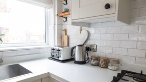 Eine moderne Küche mit weißen Schränken, einem Edelstahltoaster, einem Wasserkocher und einem Gasherd.