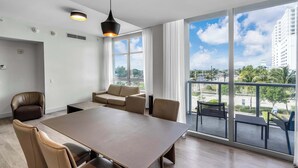A modern living room with a large table, comfortable seating, and a balcony with a city view. - Between Lakes and Ocean For 4 (Hollywood)