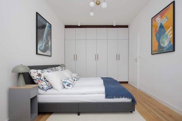 Un dormitorio con cama, mesita de noche y dos armarios empotrados.