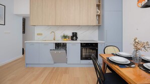 Une cuisine moderne avec des meubles de couleur bois clair, un lave-vaisselle encastré et une machine à café.
