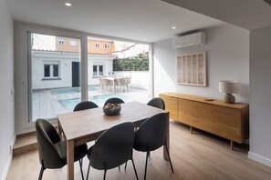 A modern dining area with a wooden table, four chairs, a bowl of decorative items, a wooden cabinet, and a wall-mounted air conditioner. - A three-bedroom in Tetuán with its own outdoor space and a separate guest house with a workspace, near La Ventilla park and the Castellana. (MADRID)
