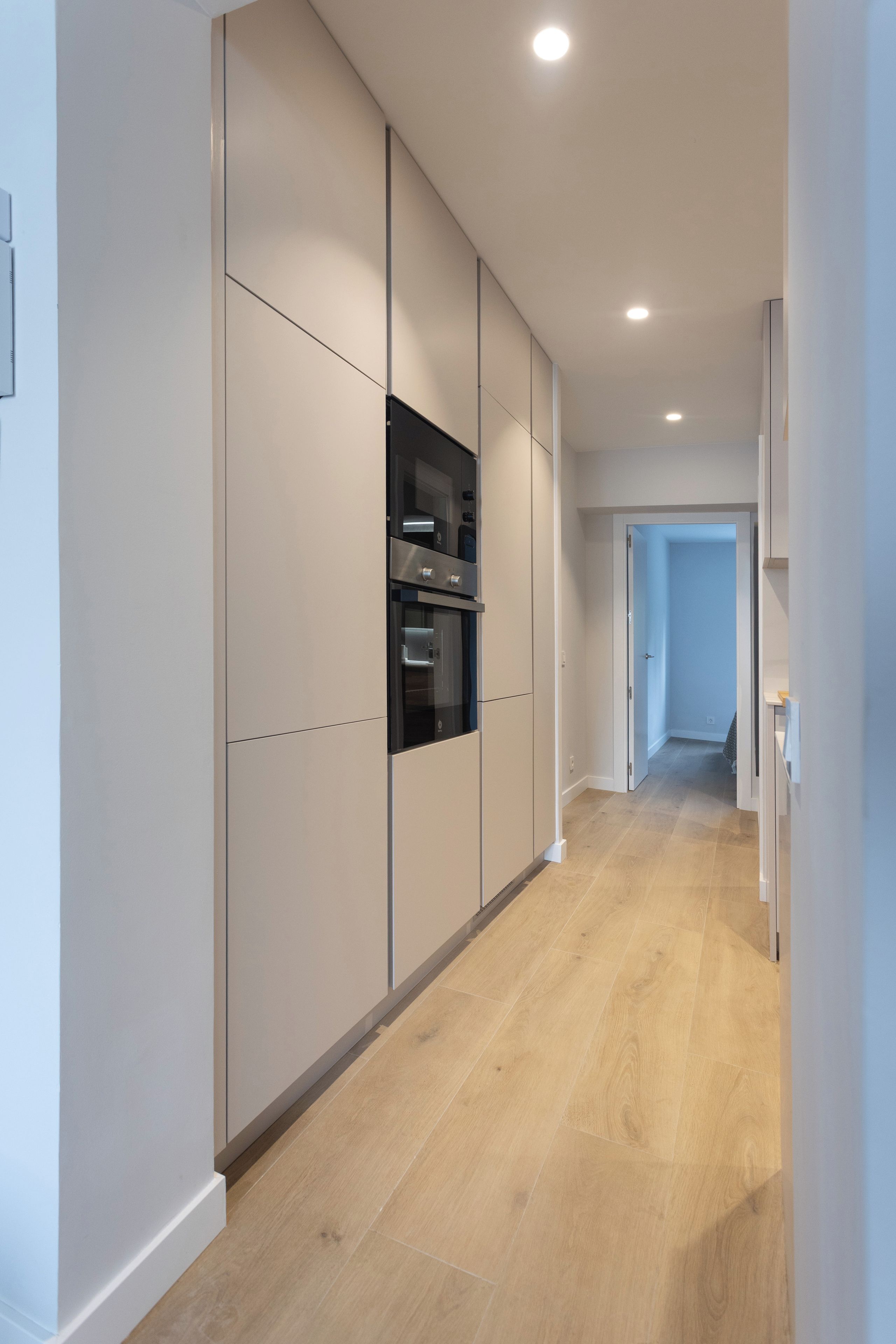 A modern kitchen with built-in appliances and a wooden floor.