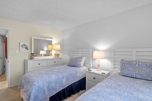 A bedroom with two beds, a dresser, a mirror, and bedside lamps. - Seaward B101 (New Smyrna Beach)