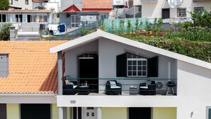 A two-story building with a balcony, a door, and a small outdoor seating area. - 2-bed apt with sea view |Ponta do Sol SeaView (Socorro)