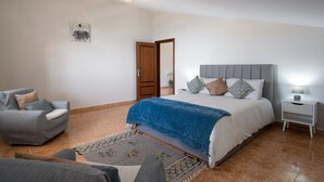A bedroom with a bed, a chair, a nightstand, and a door. - 2-bed apt with sea view |Ponta do Sol SeaView (Socorro)