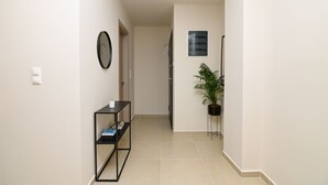 Un pasillo con una consola negra, una planta en maceta y una puerta que da a otra habitación.