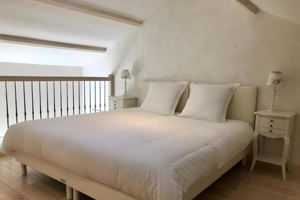 Une chambre avec un grand lit, deux tables de chevet et une vue sur l’extérieur.