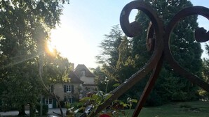 Un jardin agrémenté d’une sculpture en métal et de roses rouges.