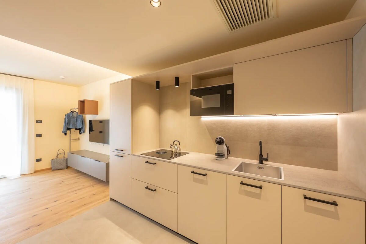 A modern kitchen with a built-in microwave, a kettle, and a sink.