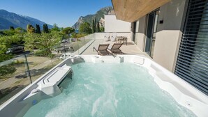 Un jacuzzi con sillones reclinables, barandilla de vidrio y vistas a la montaña.