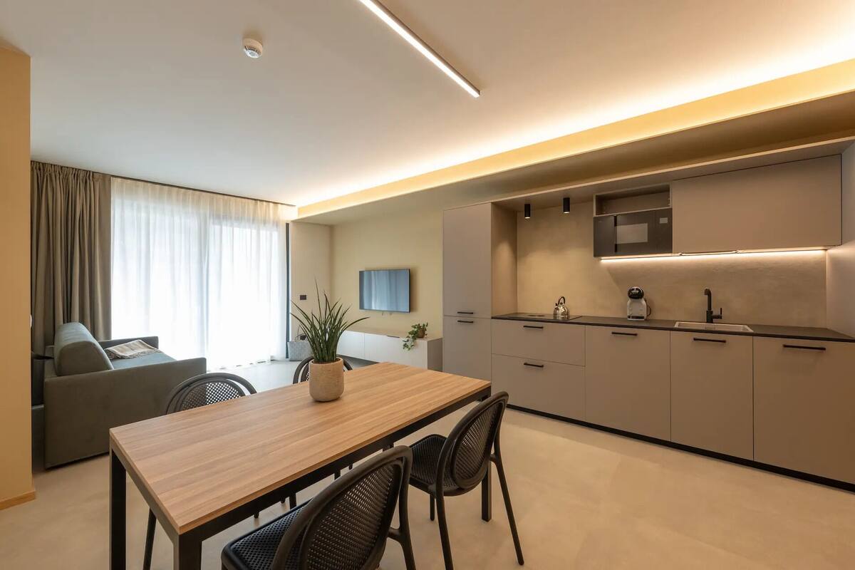 Une chambre d’hôtel moderne dotée d’un coin repas, d’une kitchenette et d’un téléviseur à écran plat.