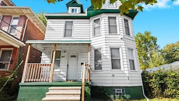 A two-story house with a green front porch, a small balcony, and a garage.