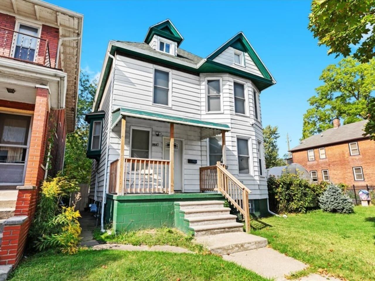 A two-story house with a front porch, a small front yard, and a visible front door.