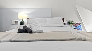A neatly made bed with white linens, a rolled-up towel, and a gray throw blanket. - The Sheridan Family Compound 4BR + 2.5BA (Detroit)
