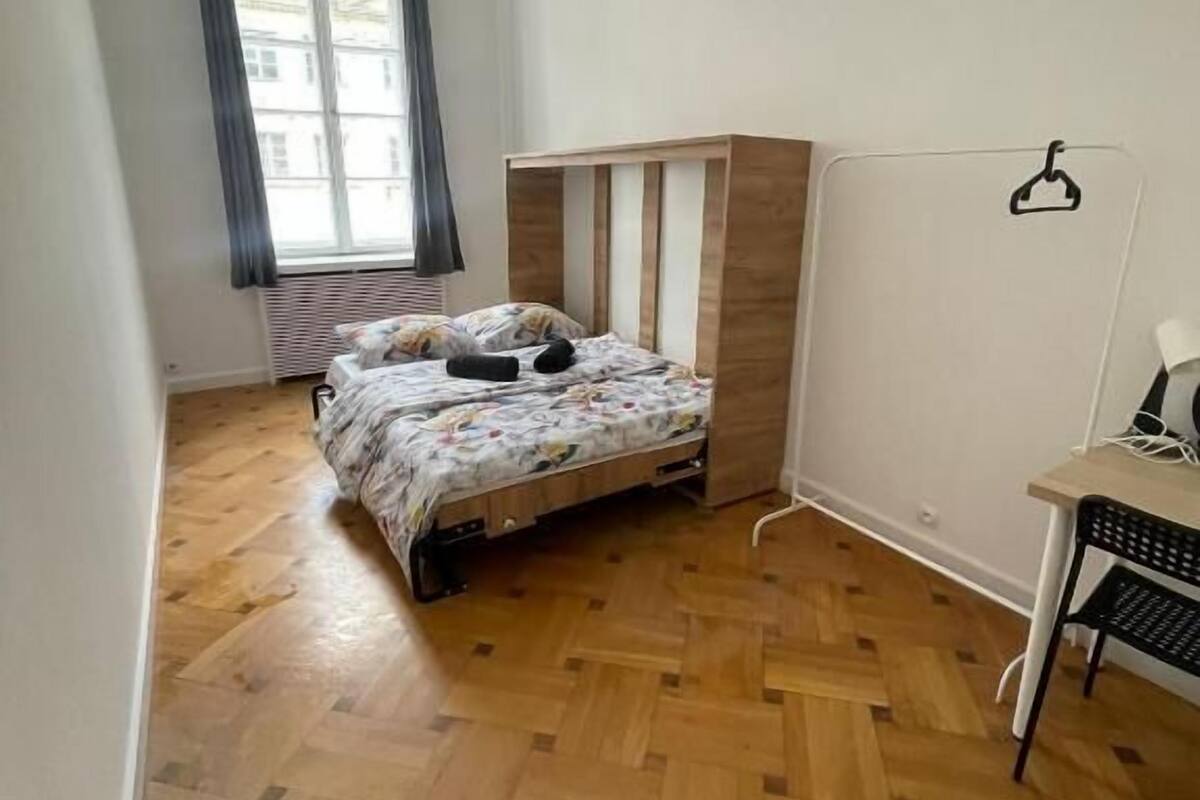 Egy hálószoba, amelyben van egy ágy, egy íróasztal és egy radiátor.