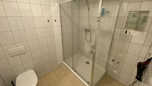 A bathroom with a glass-enclosed shower, a white toilet, and a mirror on the wall. - Fantastic Inn Warsaw - NS38 (Warsaw)