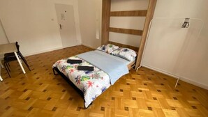 A room with a bed, a wooden floor, a door, and a chair. - Fantastic Inn Warsaw - NS38 (Warsaw)