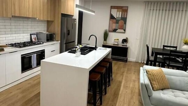 Une cuisine moderne dotée d’un îlot central, de meubles en bois et d’un coin repas avec un canapé et une table.
