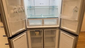Un petit réfrigérateur d’angle doté de plusieurs étagères et compartiments, dont une section à porte en verre.
