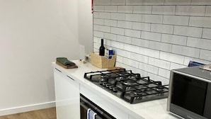 Une cuisine moderne équipée d’une cuisinière à gaz, d’un four, d’un four à micro-ondes et de meubles de rangement blancs.