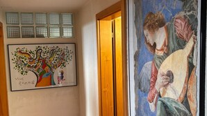 Ein Flur mit Fliesenboden, einer Holztür und zwei gerahmten Kunstwerken an der Wand.