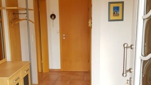 A hallway with a wooden door, a coat rack, and a blue rug leading to a room. - House Kiki in Dornumersiel (Dornum)