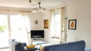 A living room with a blue sofa, a television, and a floor lamp. - House Kiki in Dornumersiel (Dornum)