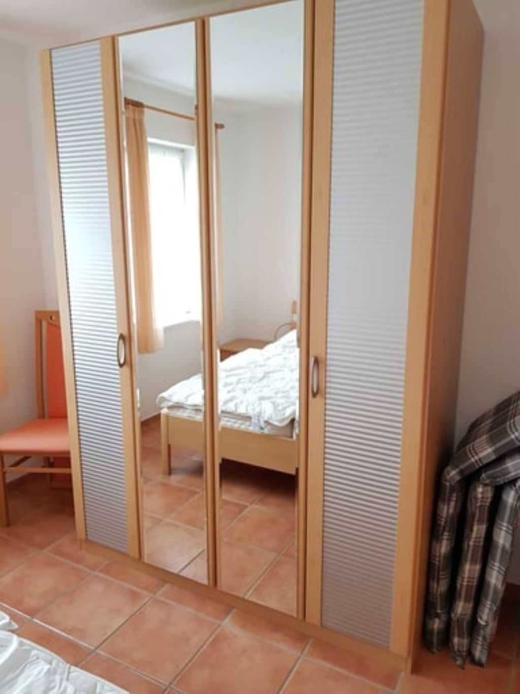 Une chambre à coucher comprenant un lit, une chaise et une armoire avec des portes coulissantes.