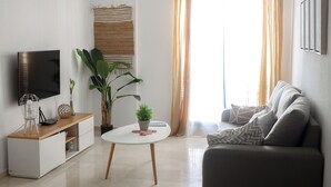 Un salon équipé d’un téléviseur à écran plat, d’une table basse, d’un canapé et d’une plante en pot.