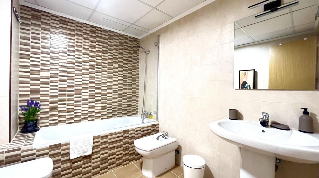 Een badkamer met een bad, toilet, wastafel en spiegel.