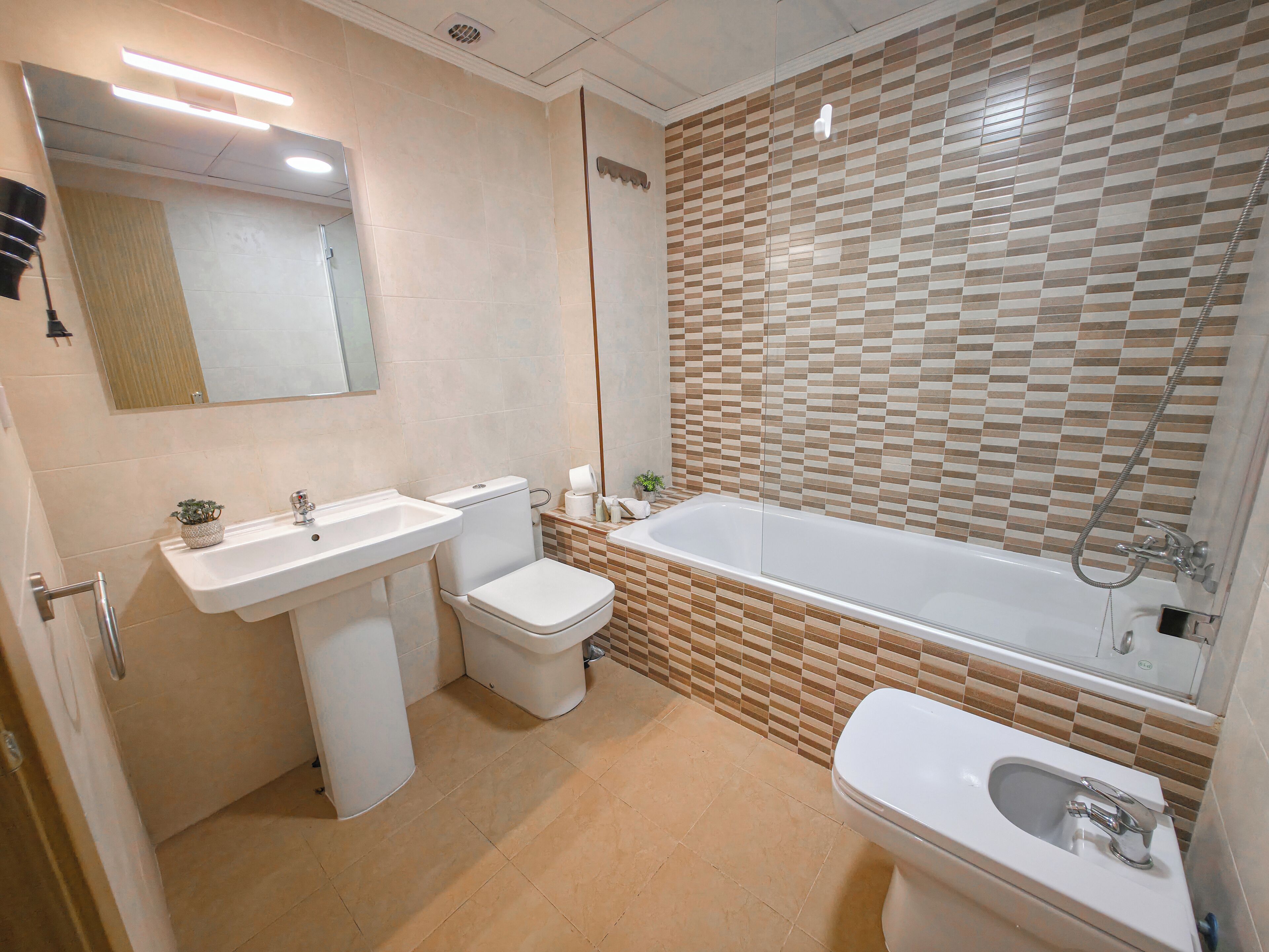 A modern bathroom with a toilet, sink, and bathtub.