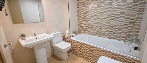 A modern bathroom with a toilet, sink, and bathtub.