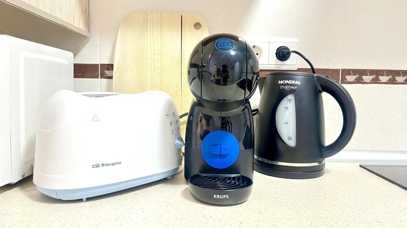 A kitchen with a white toaster, a Krups coffee maker, and a Mondial SmartHot kettle.
