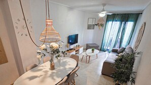 Un salon moderne comprenant un coin repas, un téléviseur et une grande fenêtre avec des rideaux.