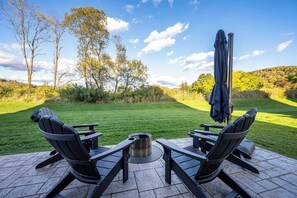 An outdoor seating area with two chairs and a table, a metal grill, and an umbrella.