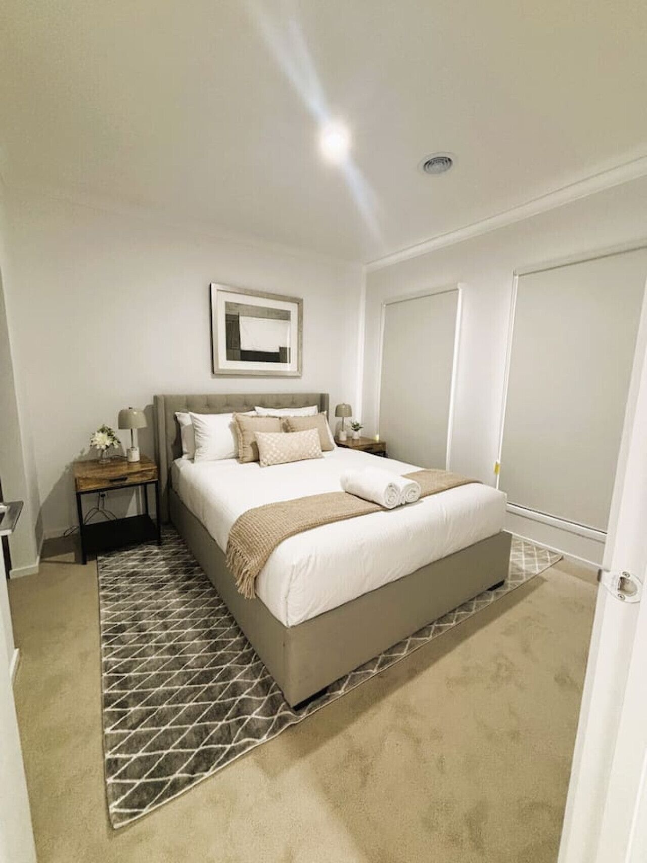A bedroom with a bed, nightstands, a framed picture, and a door.