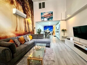 Un soggiorno moderno con un divano componibile, un tavolino in vetro e un televisore piatto.
