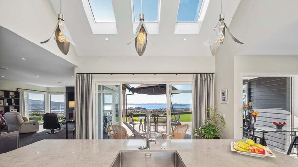 A modern kitchen with a large island, skylights, and a view of the outdoors.