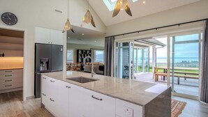 A modern kitchen with a large island, a built-in refrigerator, and a skylight.
