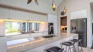 A modern kitchen with a large island, stainless steel appliances, and pendant lighting.