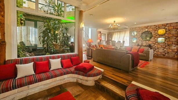A spacious living room with a large window, a stone wall, and a fireplace. - Charming seaside villa for 11 people with private pool and fireplace (Tabarka)