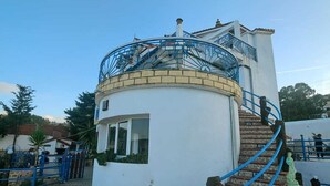 A building with a circular structure, a staircase, and a blue railing. - Charming seaside villa for 11 people with private pool and fireplace (Tabarka)