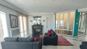 A spacious living room with a fireplace, two sofas, and a large window with a view. - Charming seaside villa for 11 people with private pool and fireplace (Tabarka)