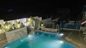 Ein Swimmingpool mit Rutsche, umgeben von Steinmauern und Topfpflanzen.