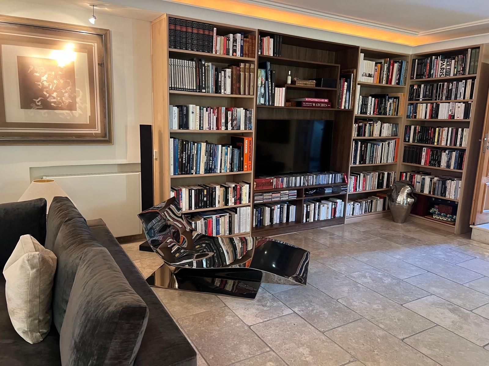 Uma sala de estar com sofá, mesa de centro e estante cheia de livros.