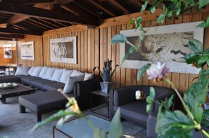 Un espace extérieur moderne aménagé avec un canapé, un pouf et une table basse.