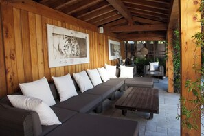 Un espace extérieur aménagé, abrité et doté d’un canapé et d’une table basse, de murs en bois et d’un tableau encadré accroché au mur.