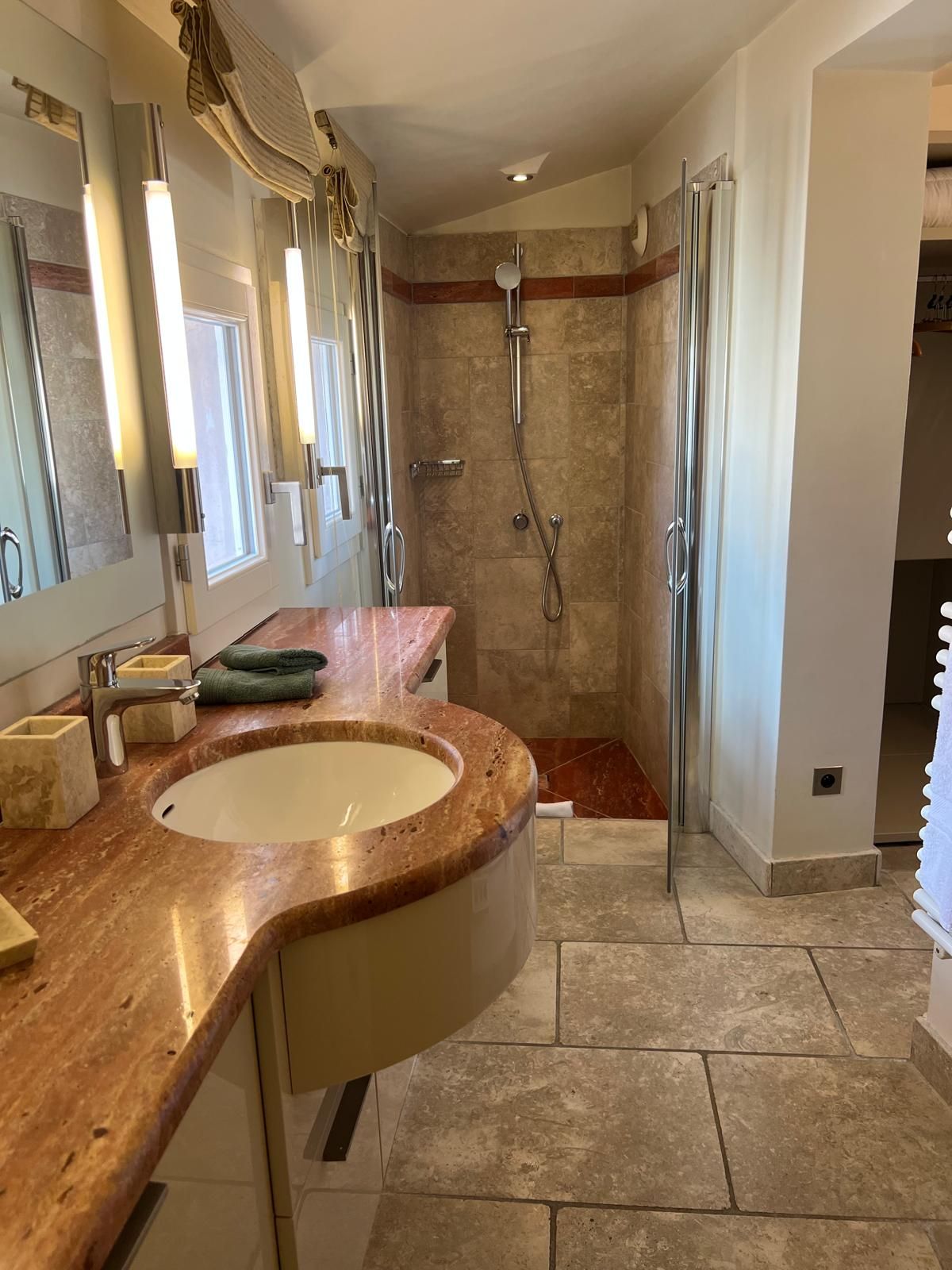 Ein Badezimmer mit einem Becken in gebogener Form, einer Dusche und einer begehbaren Dusche.