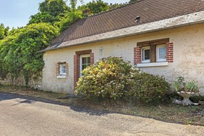 A single-story building with a sloped roof, a small porch, and a gravel driveway. - Gîte Mélany for 4 Guests (Chargé)